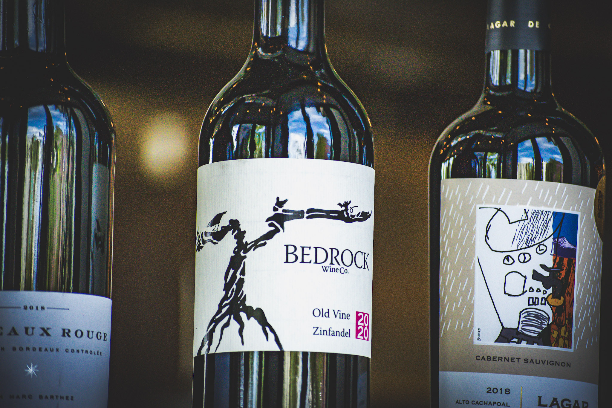 ImageA neatly arranged row of wine bottles displayed on a wooden shelf, showcasing various labels and colors.