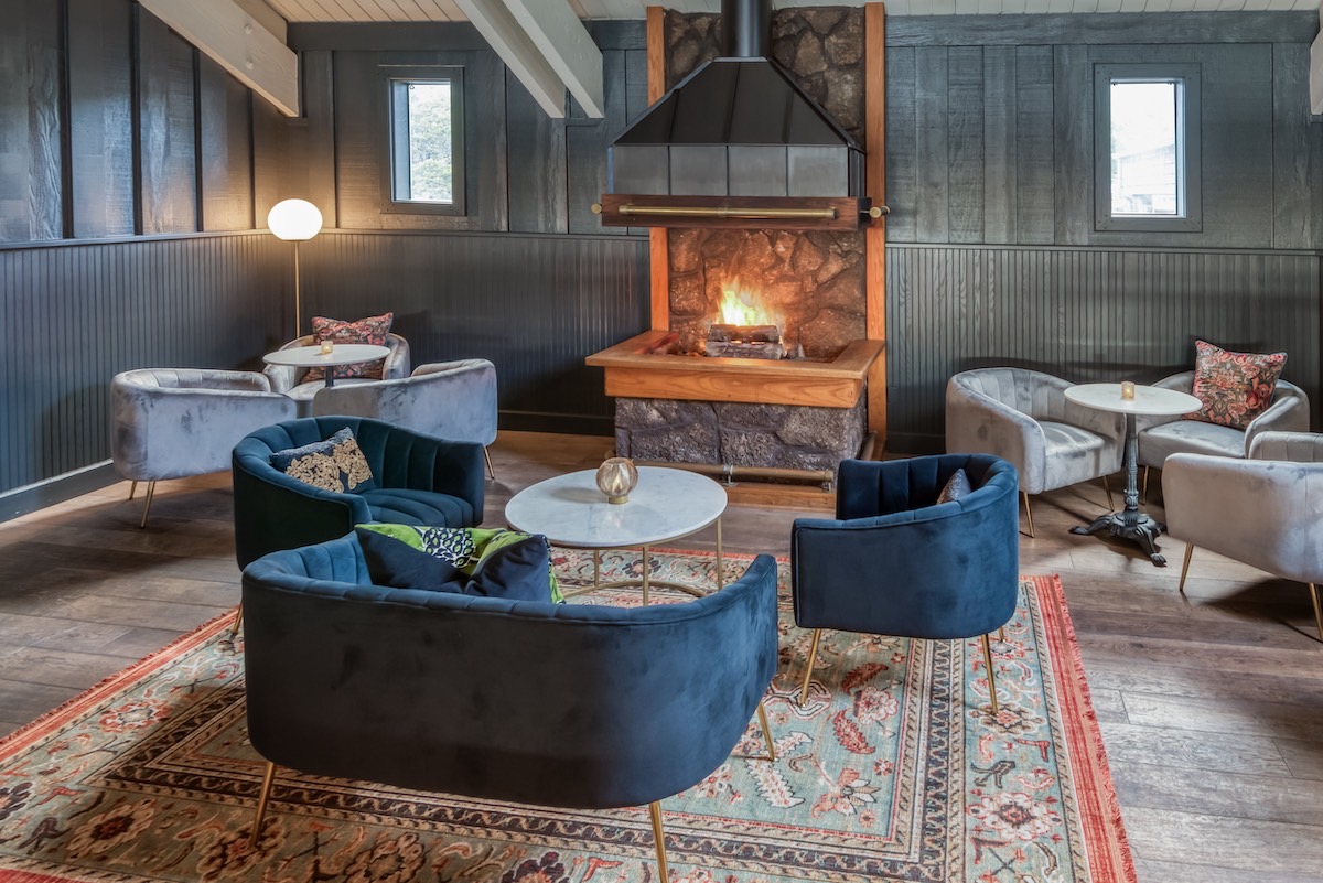 A cozy lodge living room at the summit, featuring rustic decor, comfortable seating, and large windows showcasing mountain views.